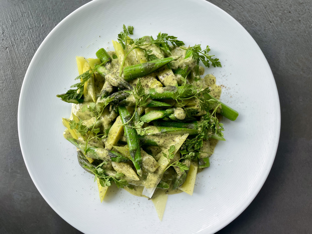 A beautiful plate of bright green cooked asparagus with mustard and chervil